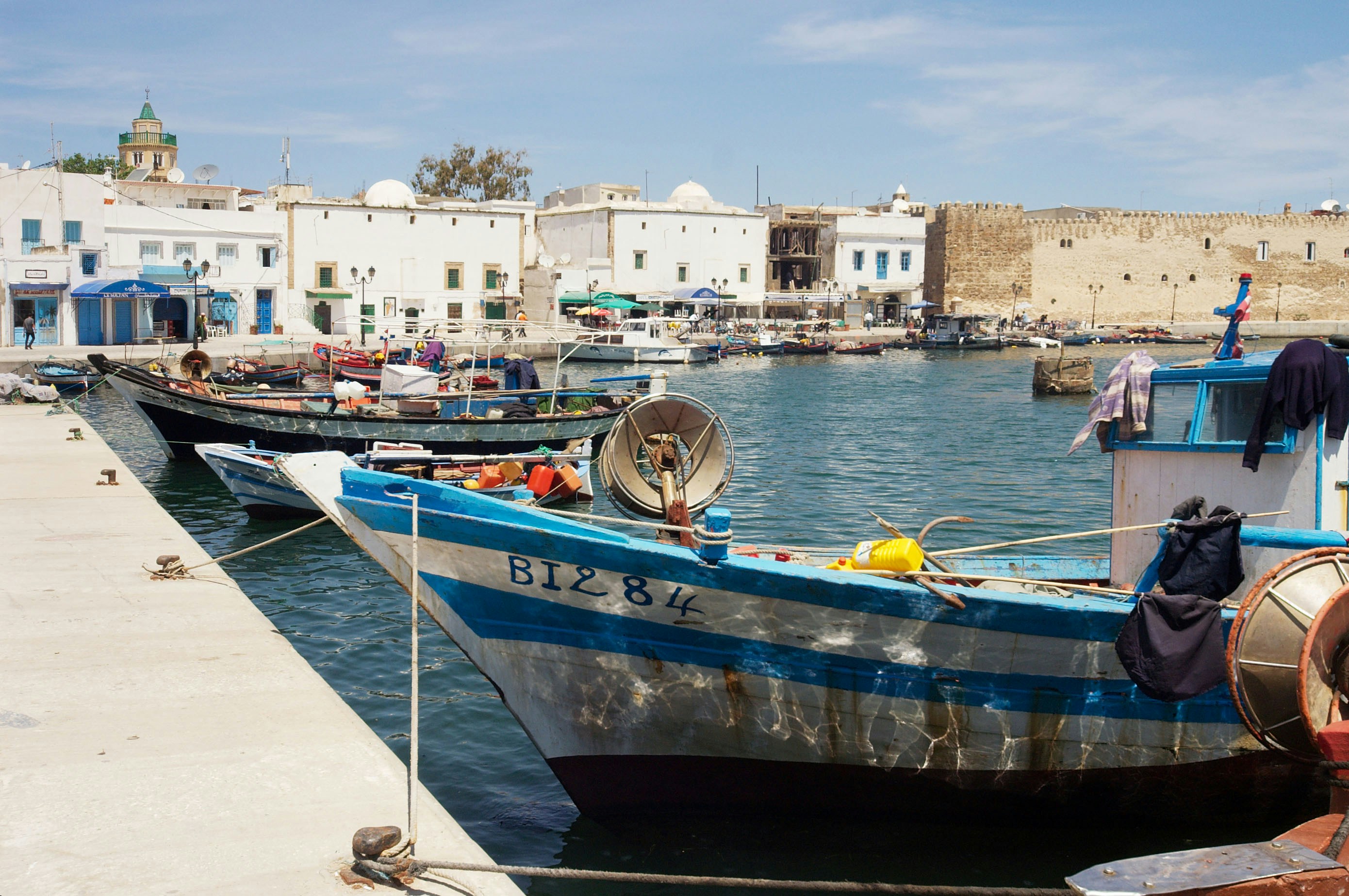 Vieux port de Bizerte avec maisons ocres et bleues, barques de pêcheurs et kasbah ottomane en arrière-plan