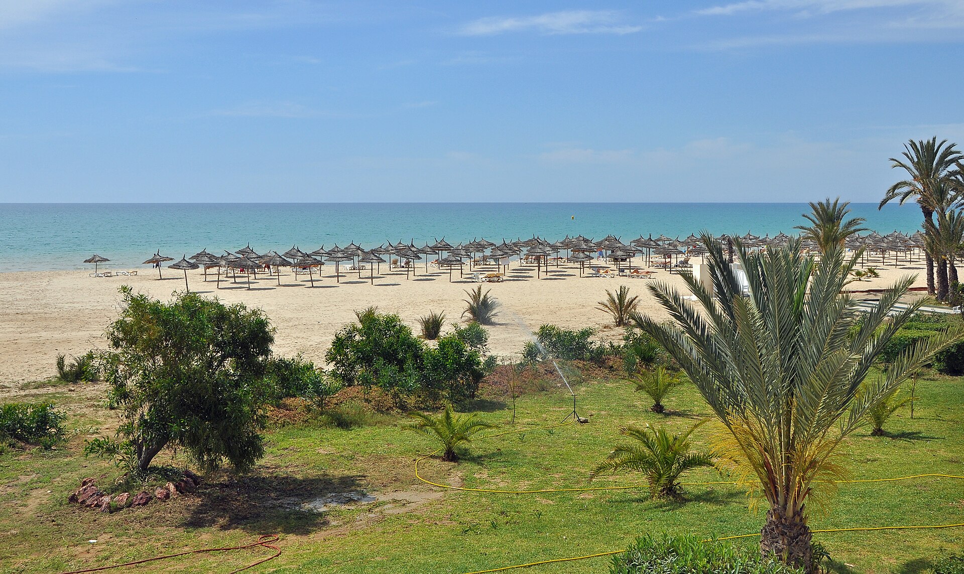 Couple senior en bord de mer à Hammamet, paréos blancs, dégustant le thé à la menthe sur une terrasse de villa